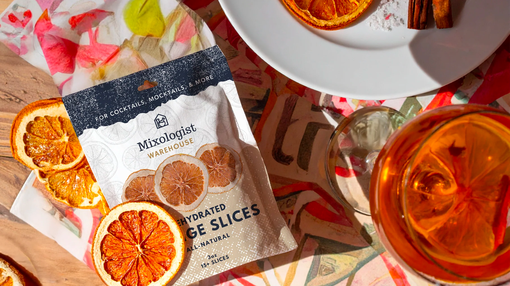 Packaged dried orange slices with a cocktail and orange slices on a table